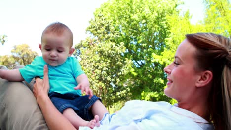 madre feliz jugando con su hijo bebé en el parque