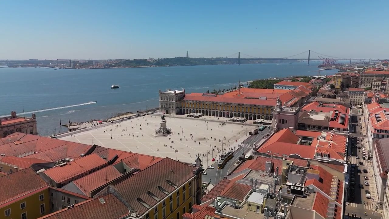Il drone si avvicina e sale sopra Praça do Comércio, mostrando i tetti di Lisbona, il fiume Tago e panorami del ponte.