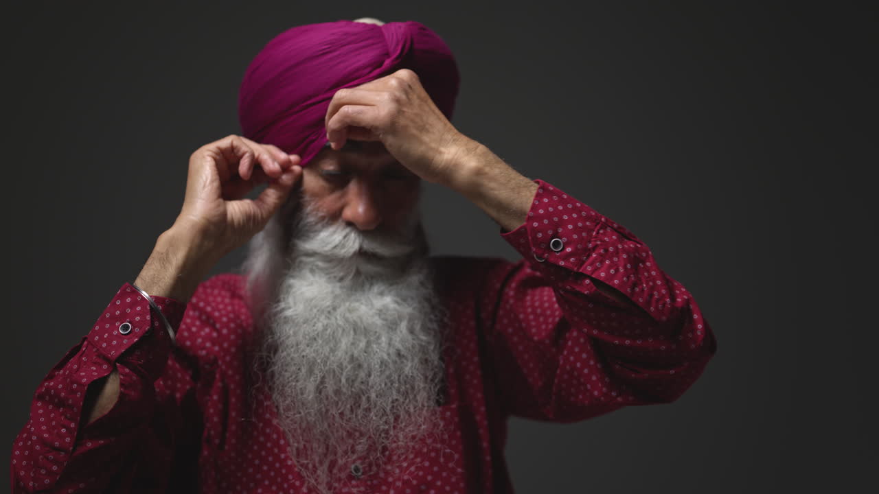 close up low key studio lighting shot de un anciano sikh con barba atando tela para turbante contra un fondo oscuro shot en tiempo real 1