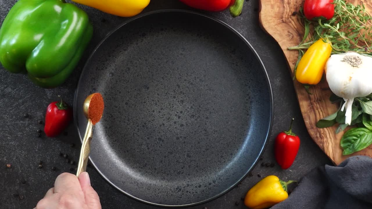 Making a vibrant Cajun Spice Blend, mixing red paprika, cayenne pepper, oregano, thyme, white garlic onion powder and black pepper in a bowl, creating a striking contrast against a black background.