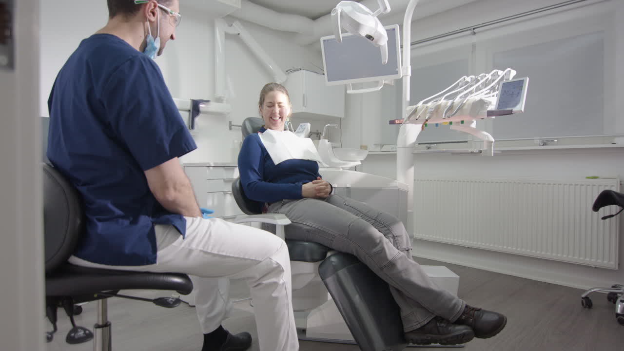 Male dentist talking to female dental patient after oral examination, slider