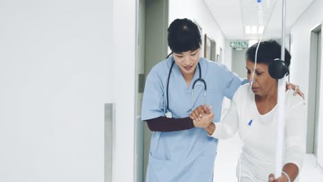 young female doctor helping senior patient walk in hospital corridor 4k