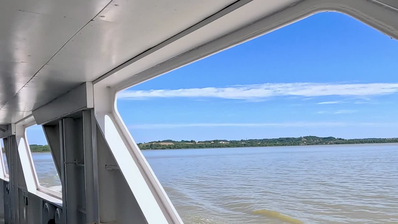 Experience the tranquil river landscape framed by the boat's interior structure.