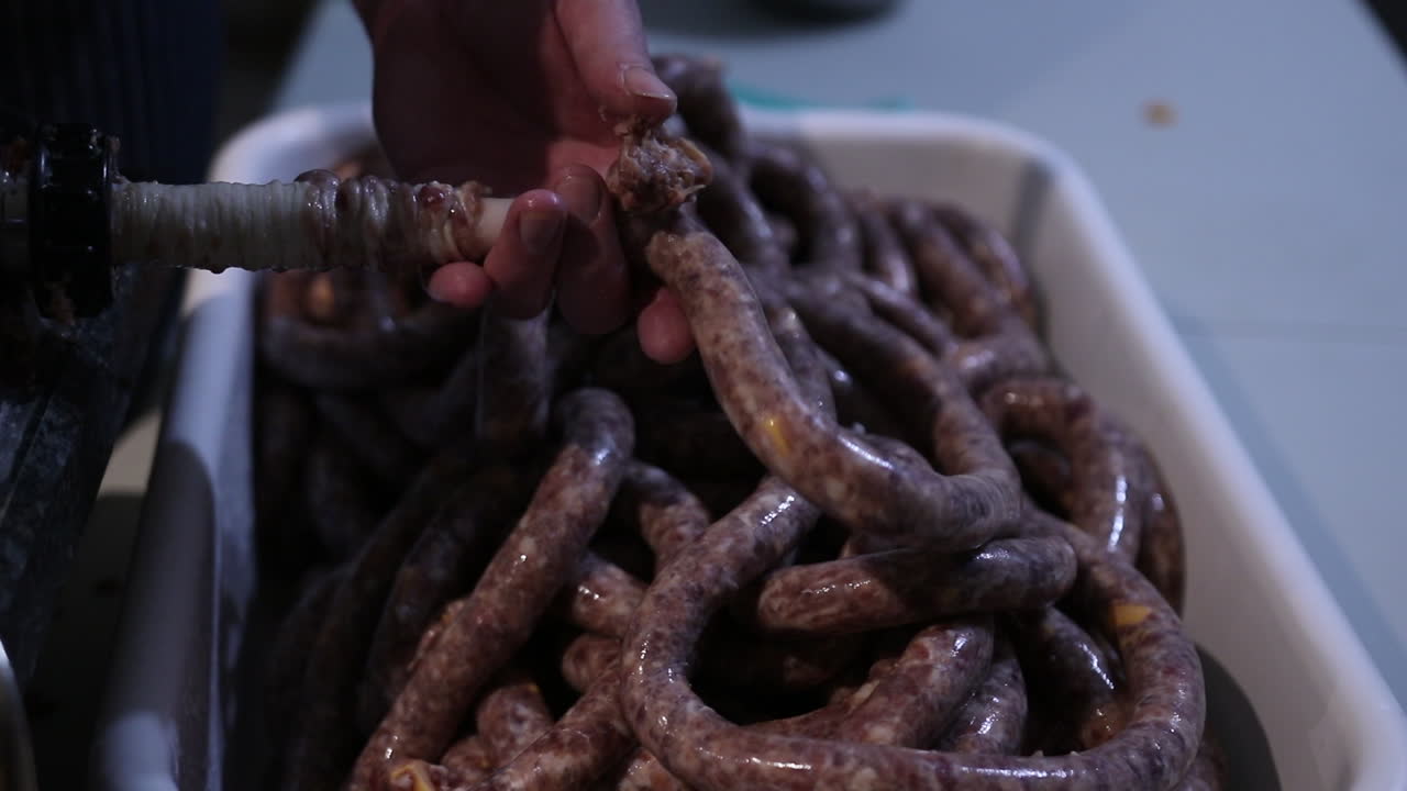 Insaccare la salsiccia - Riempire il budello di maiale con carne macinata usando un'insaccatrice - primo piano.
