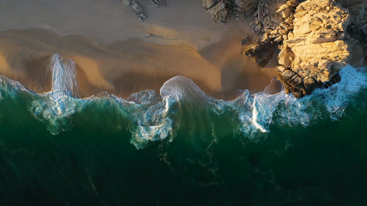 Cinematic downward angle drone shot of the waves and beautiful beaches in Cabo San Lucas Mexico