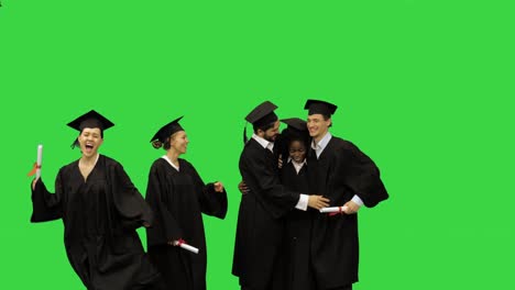 happy students congratulating each other after the graduation ceremony on a green screen, chroma key