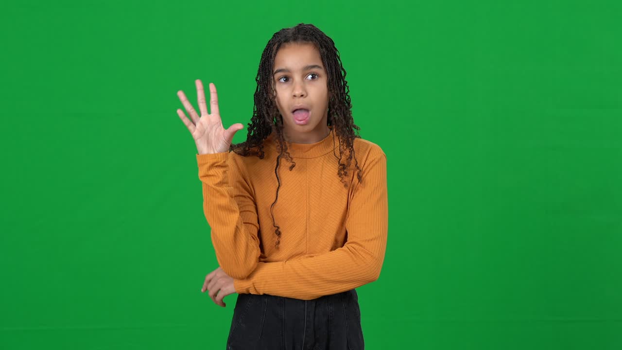 Irritated bored teenage girl rolling eyes gesturing saying bla-bla on green screen. Portrait of annoyed African American teenager posing at chromakey background.