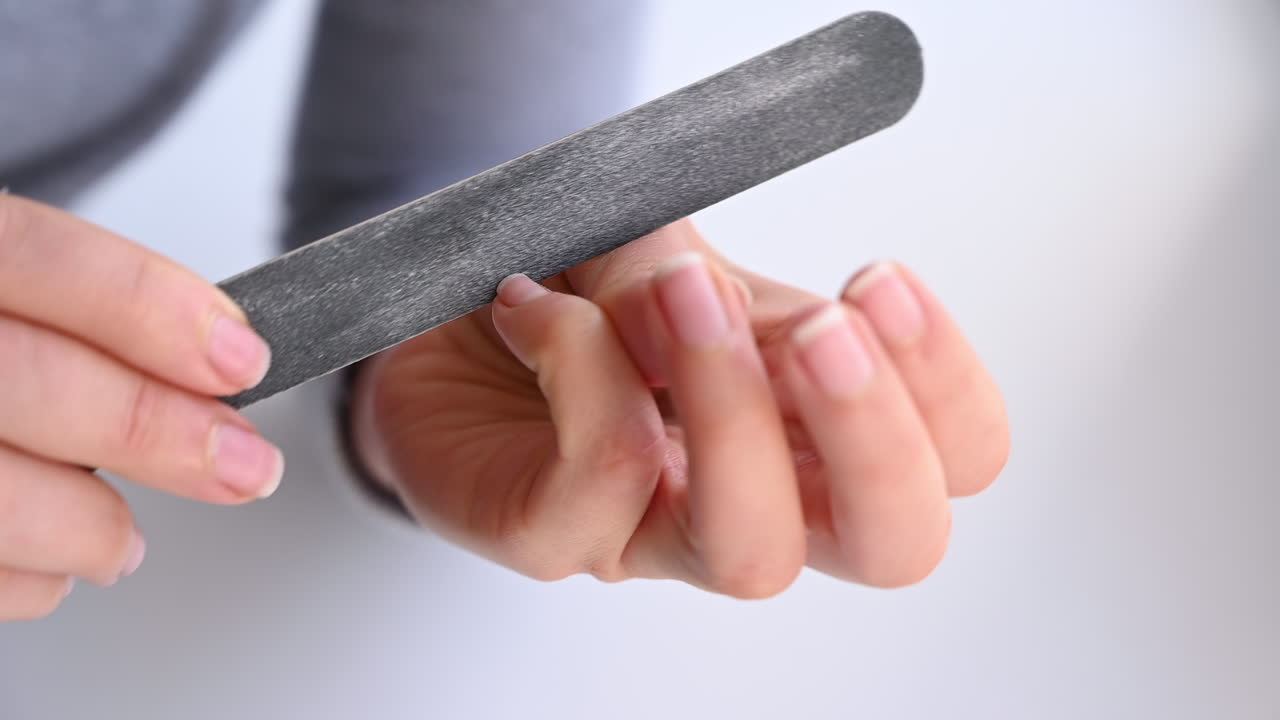 Close up of hands filing nails with a grey nail file during a self care routine