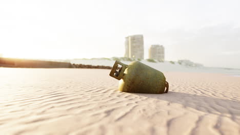 rusty gas cylinder on a beach at sunset