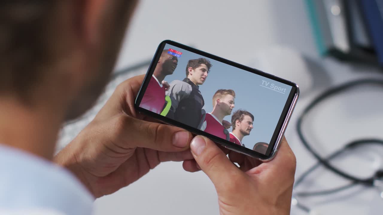 compuesto de un médico masculino viendo un evento deportivo de atletismo en un teléfono inteligente