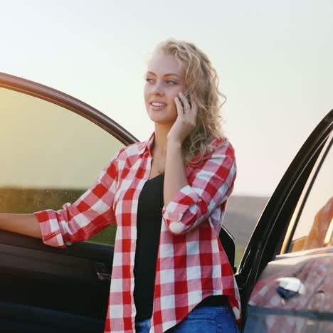 una mujer está hablando por teléfono junto a un coche 2