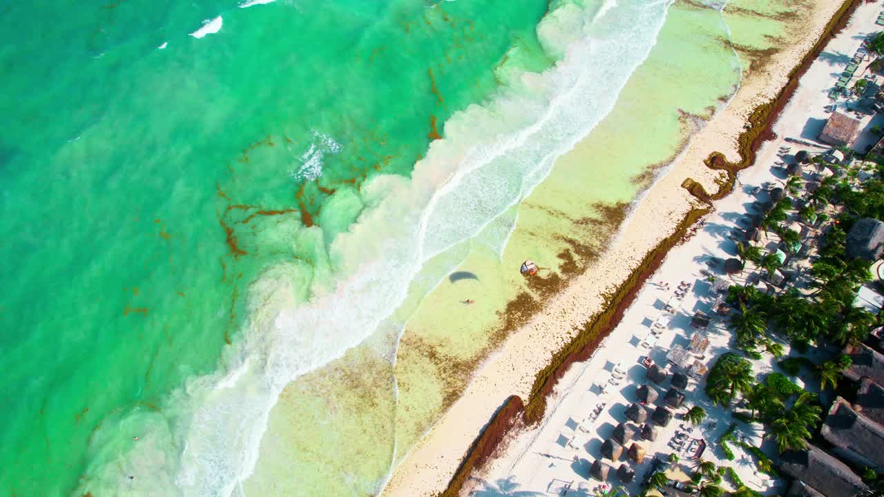 imágenes aéreas de drones dando vueltas alrededor de una cometa de parafina volando en una playa tropical caribeña