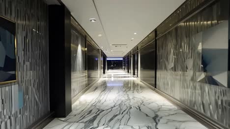 camera gliding through a modern luxury hotel corridor featuring elegant marble walls and a polished floor