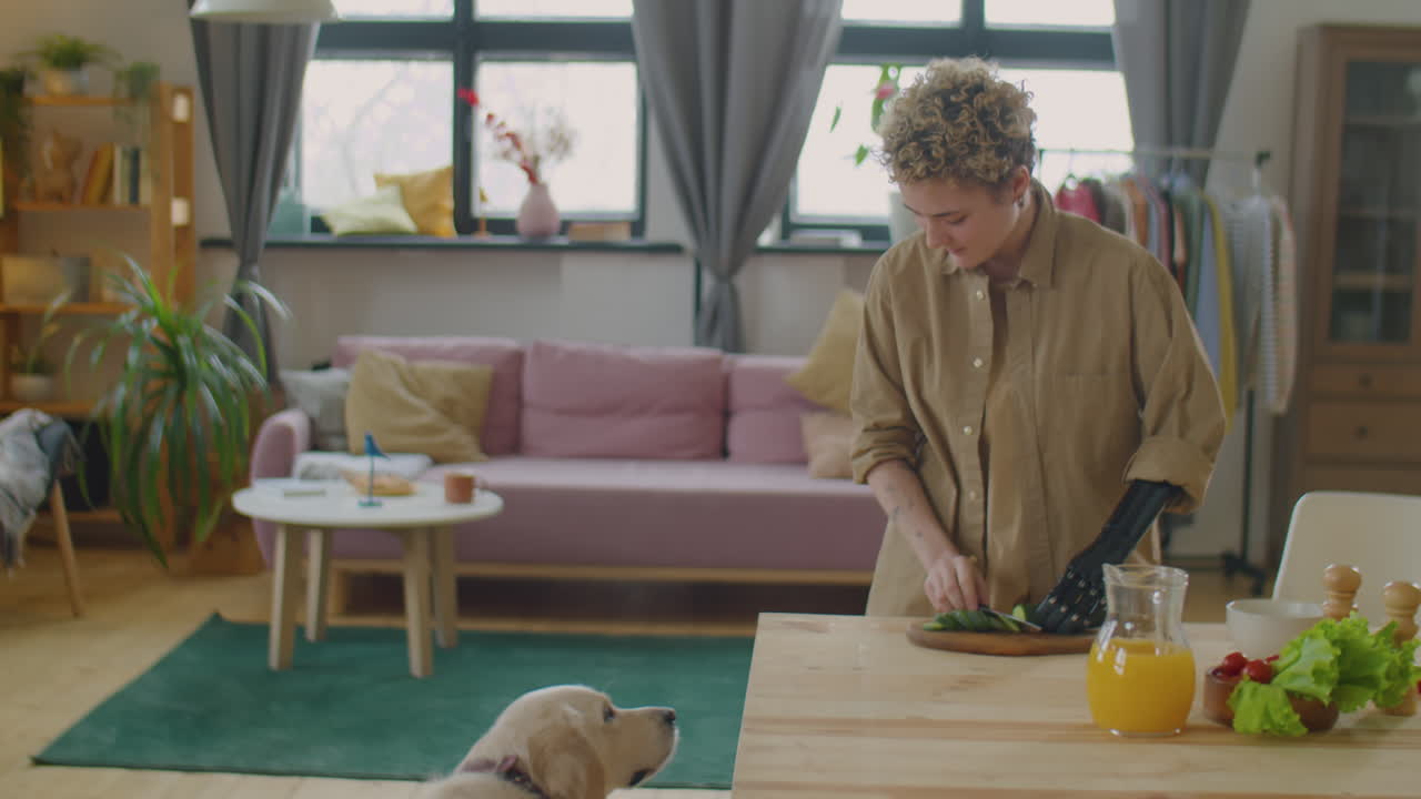 Girl with Prosthetic Arm Cooking Food and Treating Dog at Home