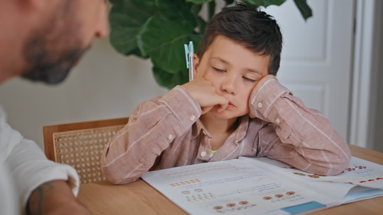 Closeup boy doing homework together with father in room. Child listening parent