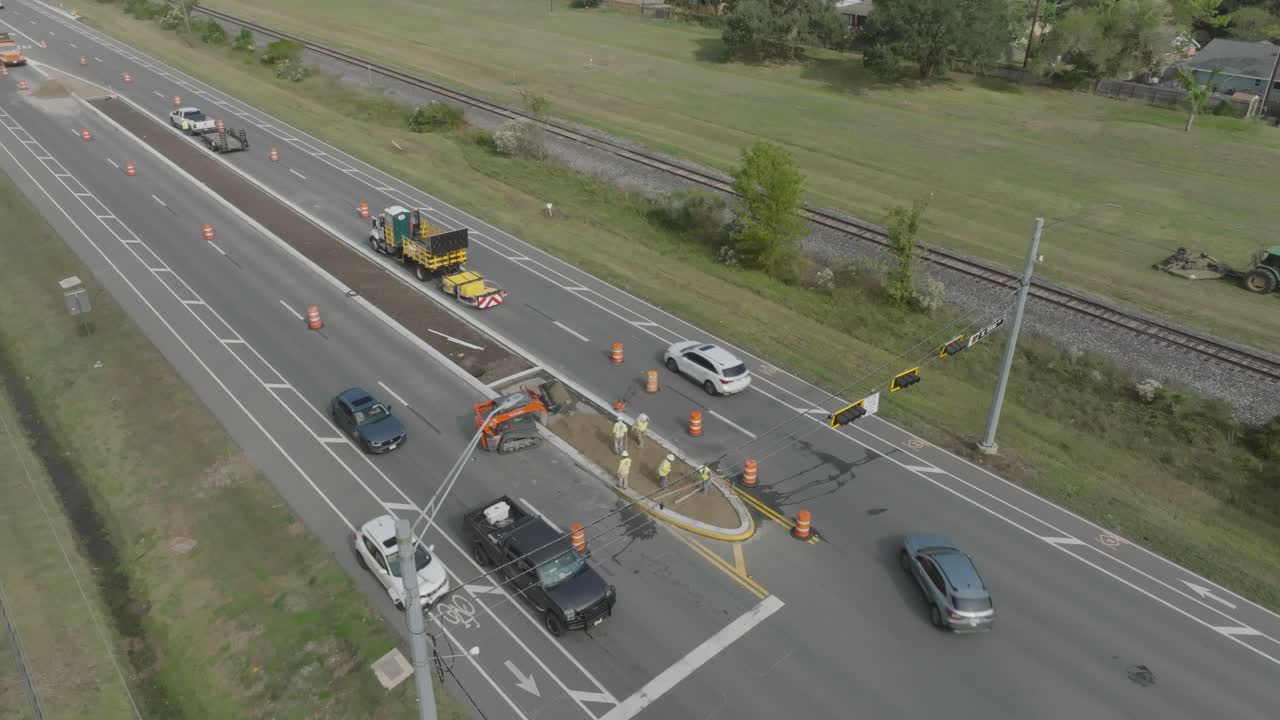 A 4K drone view captures a road construction crew working on the median of Highway 3, while a tractor operator with a brush hog maintains the highway and railroad easements in Houston, Texas.