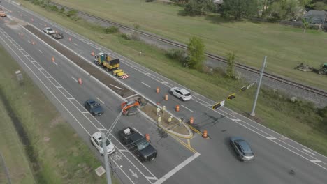 a 4k drone view captures a road construction crew working on the median of highway 3, while a tractor operator with a brush hog maintains the highway and railroad easements in houston, texas.