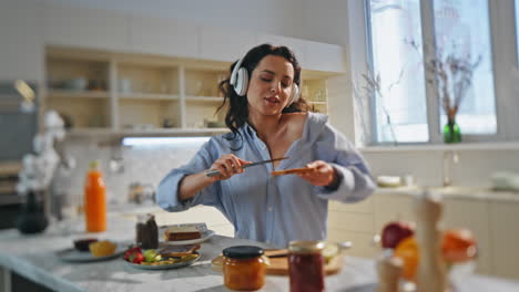 niñas con auriculares cocinando el desayuno en la cocina. mujer cantando su canción favorita