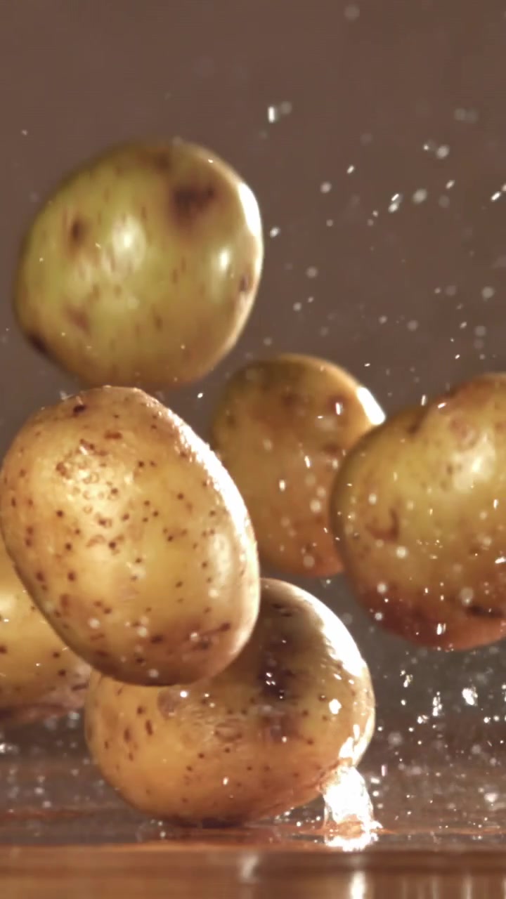 Ripresa al rallentatore di patate crude che cadono e schizzano acqua