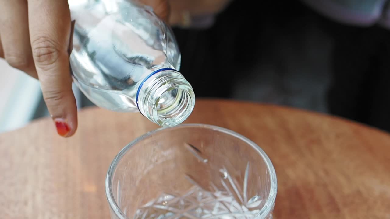 vertiendo agua de una botella en un vaso