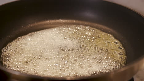 close up of butter frying in a pan - handheld