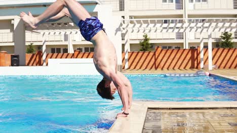 Joven-Atlético-En-Shorts-De-Baño-Corriendo-Y-Saltando-A-La-Piscina-Parado-En-Sus-Manos.-Disparo-A-Cámara-Lenta.