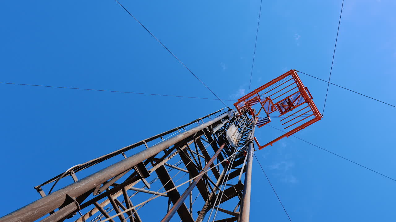 Looking at the tall metal support at the site for oil production. Low angle view at the derrick for drilling gas.