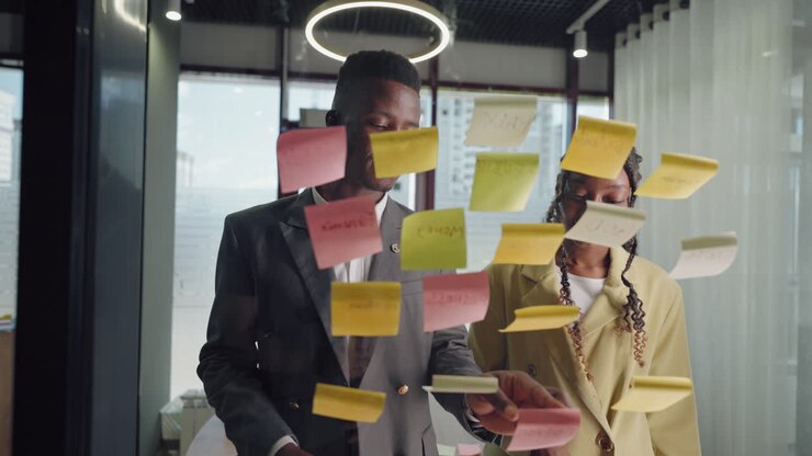 office workers sticking notes on glass in office brainstorming and generating idea for business
