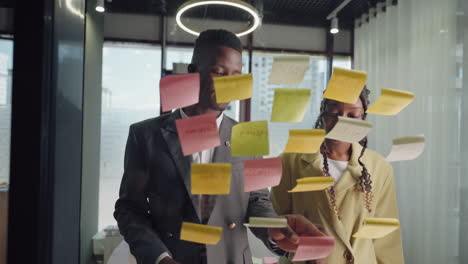 office workers sticking notes on glass in office brainstorming and generating idea for business