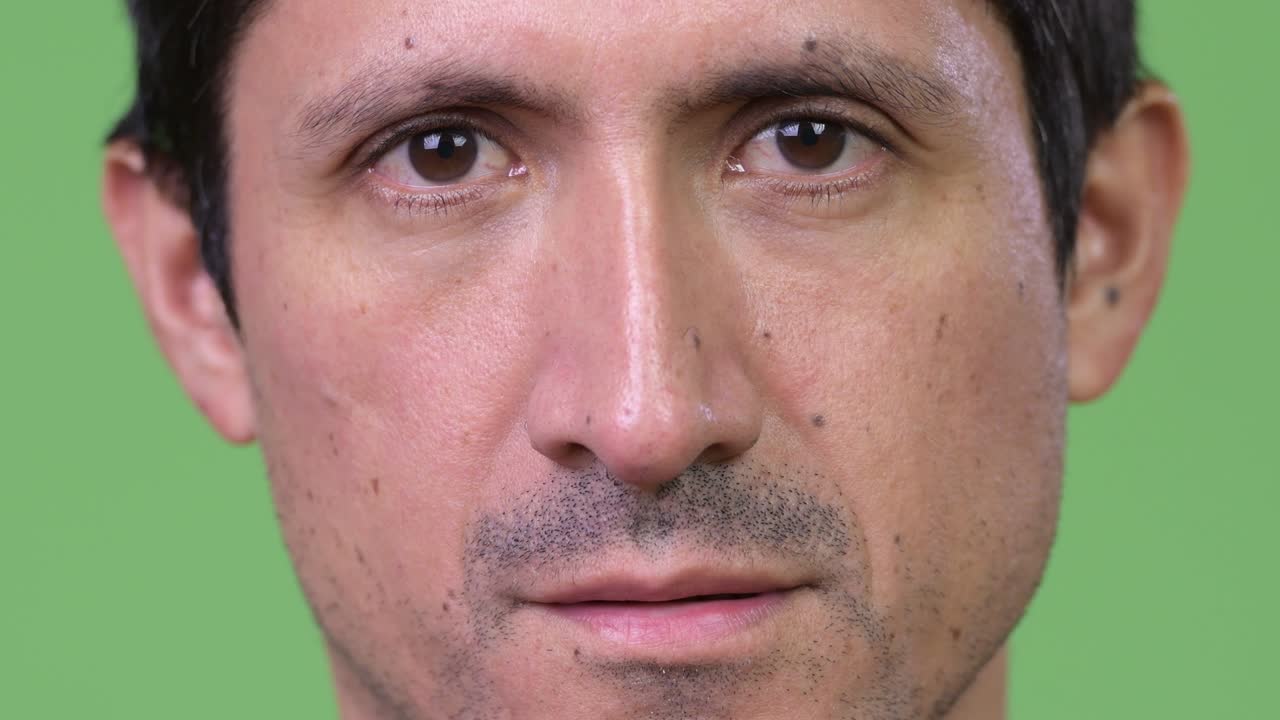 Face of Hispanic man against green background