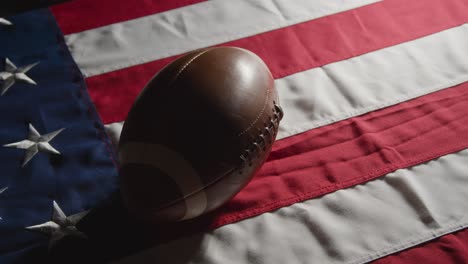 low key lighting studio shot of american football on stars and stripes flag 7