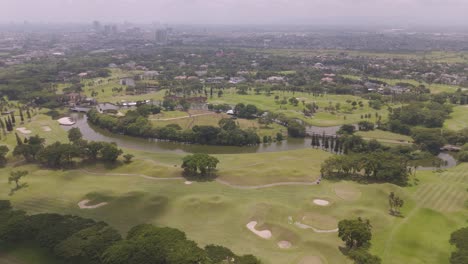 Aerial scenic view of a vibrant green golf course with a stunning city skyline in the background at Jakarta, Indonesia