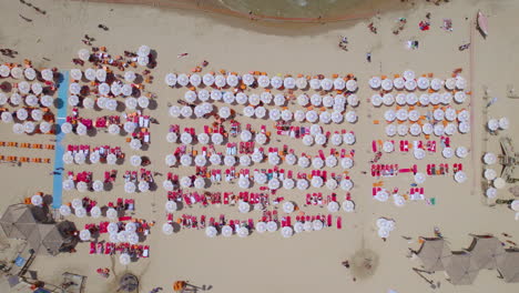 Die-Große-Menge-Bunter-Sonnenschirme-An-Den-Stränden-Von-Tel-Aviv-Mit-Roten-Sonnenliegen-Und-Orangefarbenen-Plastikstühlen-An-Einem-Gewöhnlichen-Sommertag-–-Abstrakte-Ansicht-Von-Oben