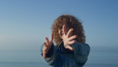 Junge-Frau-Hält-Sich-Die-Hände-Vors-Gesicht.-Verspieltes-Mädchen,-Das-Am-Strand-Mit-Der-Kamera-Flirtet