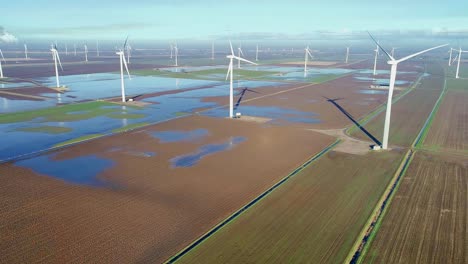 an aerial view of wind turbines in a wind farm turning slowly on a bright hazy day