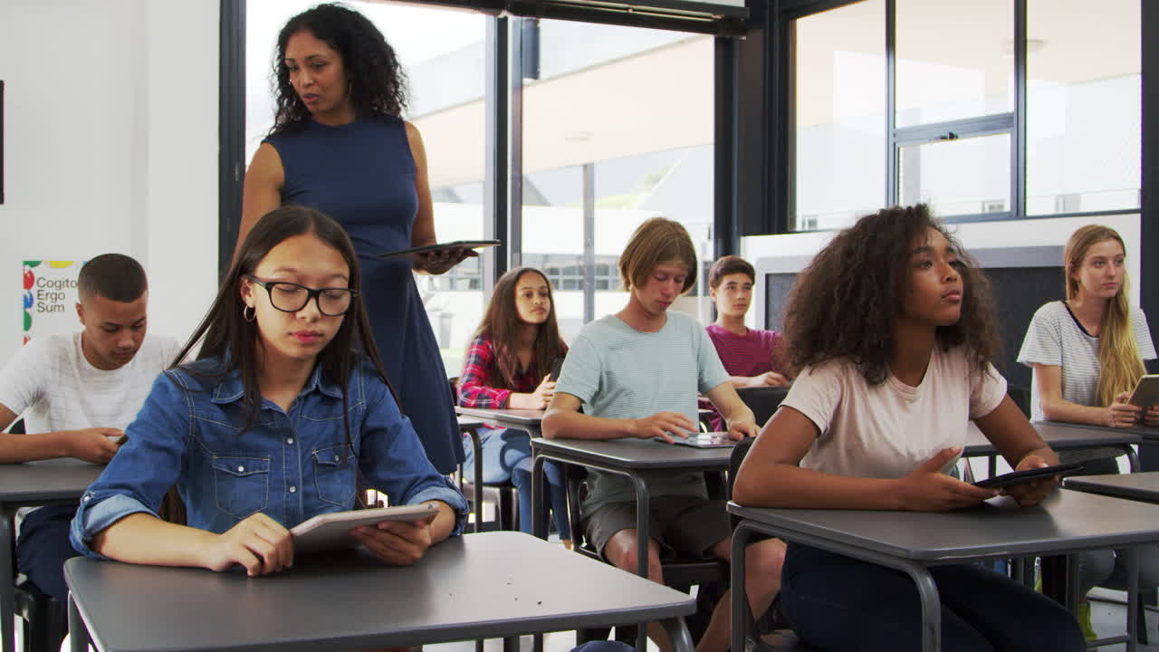 maestra dirigiéndose a los alumnos desde la parte de atrás de su clase de secundaria