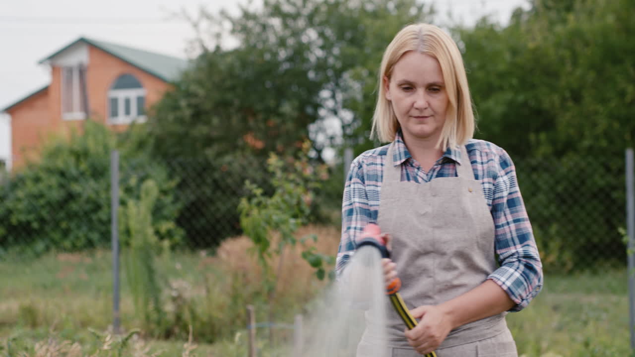 una mujer regando plantas en su jardín