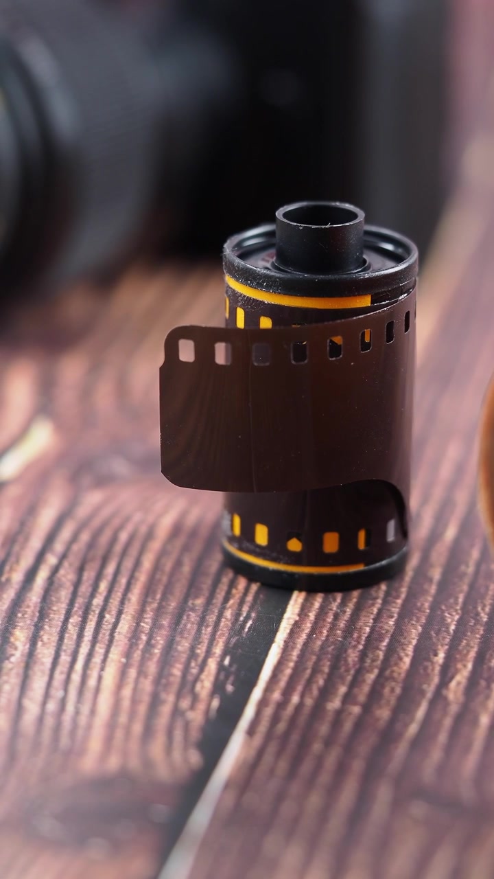 Pellicola vintage da 35mm che si srotola dalla custodia su un tavolo di legno