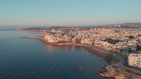 drone aerial view lowering over bay , spanish coastal town during golden hour