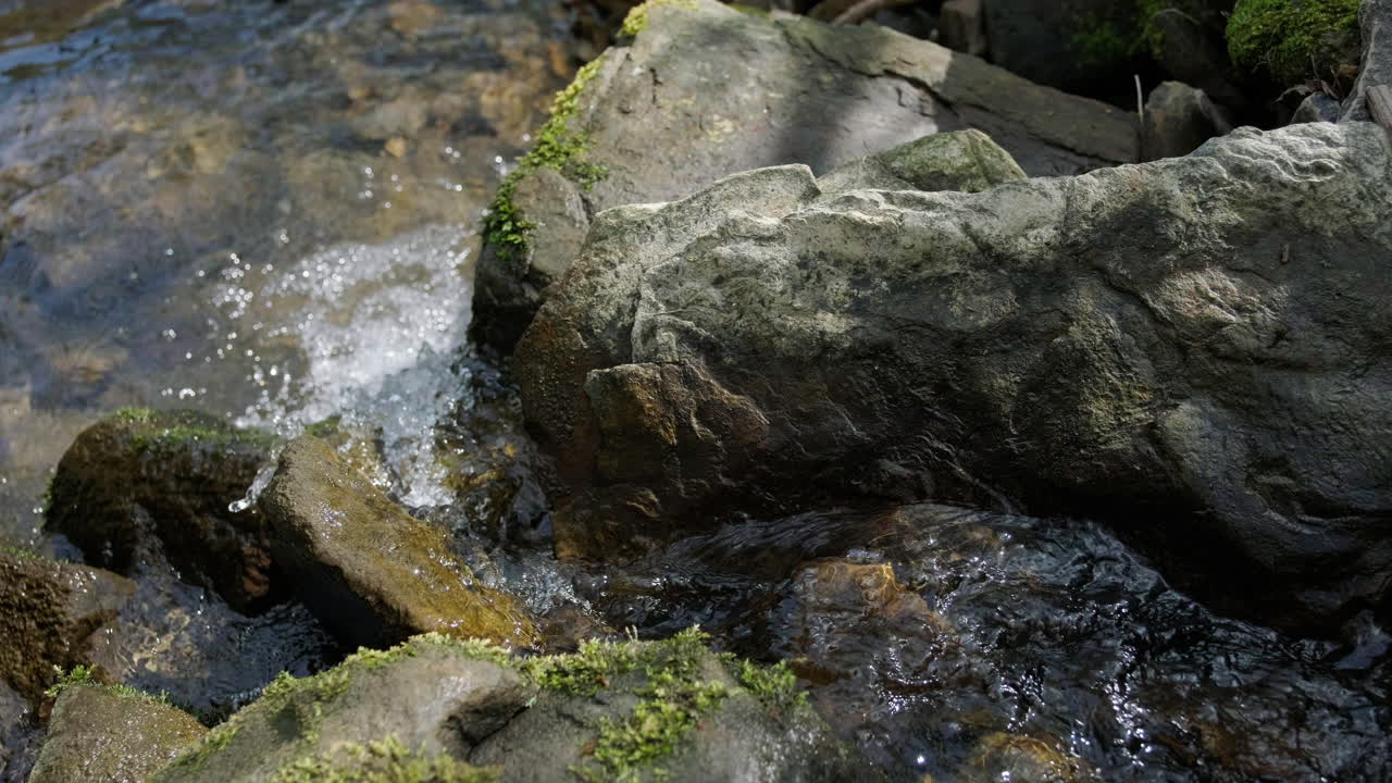 Mountain river flowing fast into stream on moss covered rocks