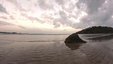 Timelapse-of-Seas-Waves-During-Cloudy-Sunset-with-Rock-in-Front-Showing-a-Tropical-Holiday-or-Vacation-Evening