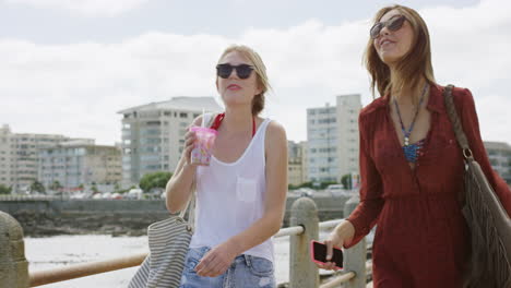 two young women pointing at view on beach promenade enjoying carefree vacation