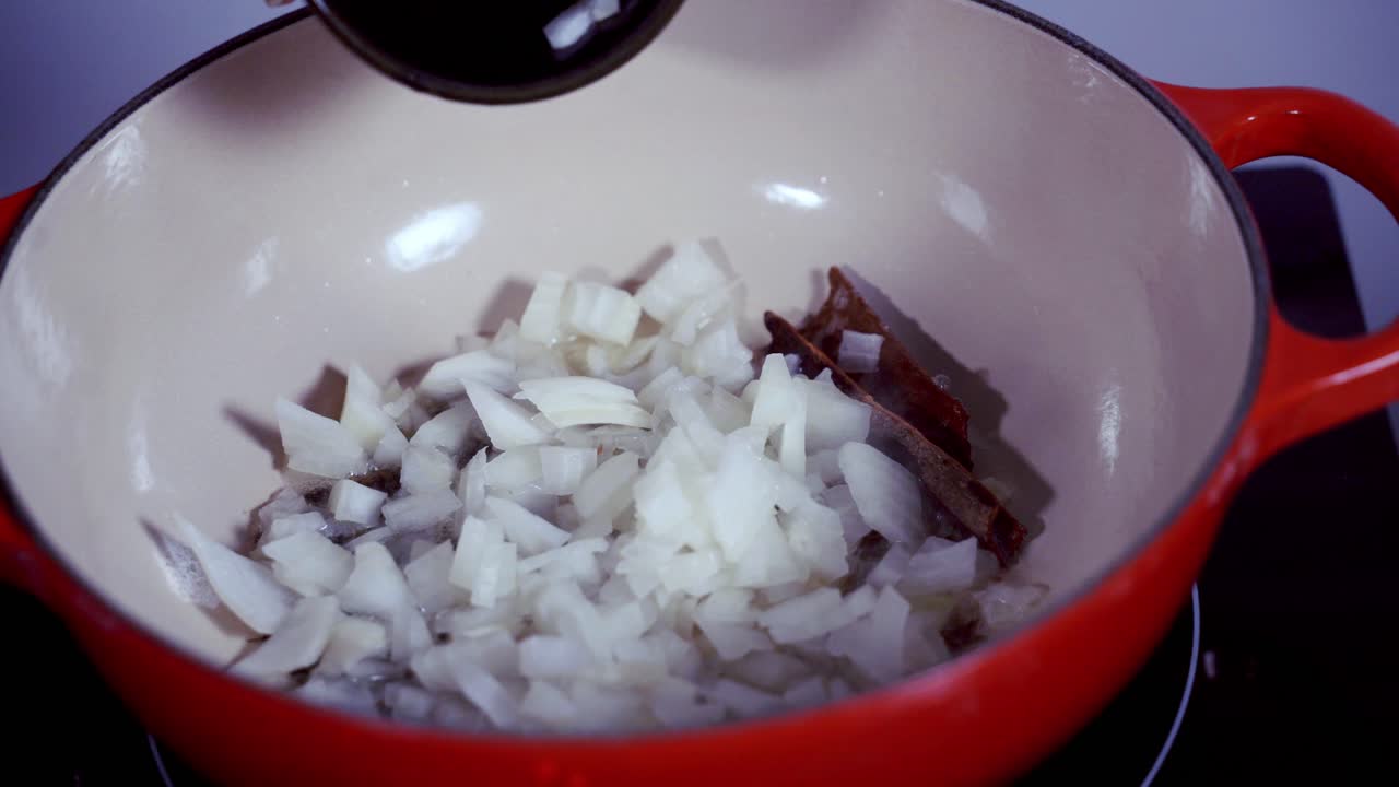 Adding onions to a pot of ingredients to prepare and make fresh green papaya curry