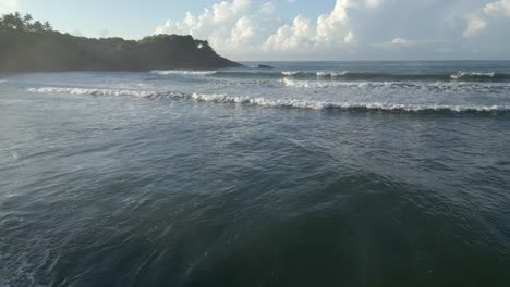 Establishing-Aerial-Drone-Shot-Flying-Out-Towards-Sea-and-Headland-from-Rocky-Beach-with-Waves-Breaking-on-Sunny-Day-in-Southern-Sri-Lanka-Coast