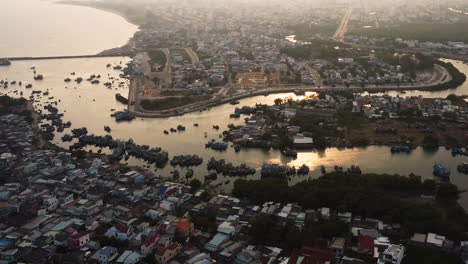 aerial slow zoom, rural coastal fishing town slum panorama during golden hour