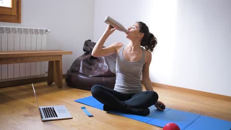 deportista sedienta bebiendo agua durante el entrenamiento en casa