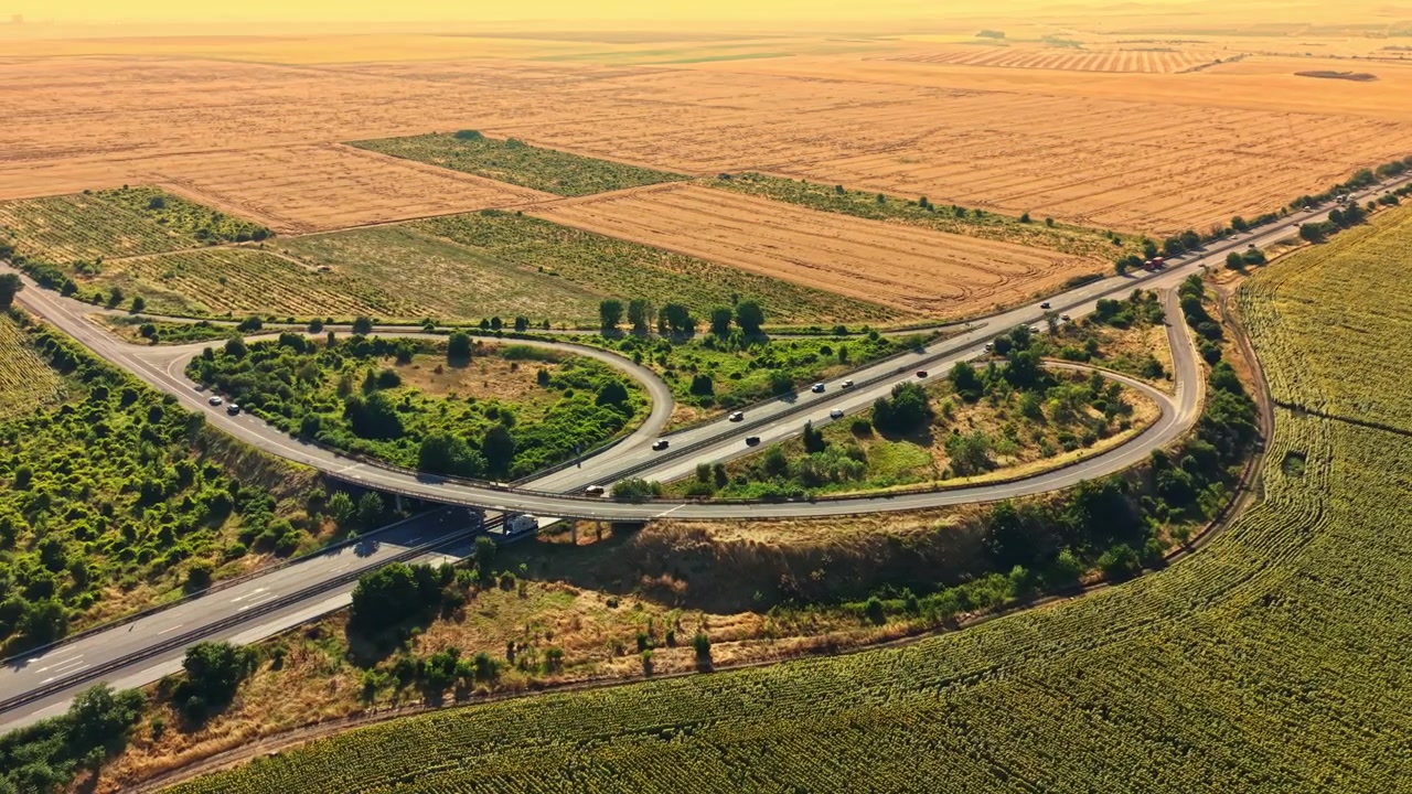 Autopista concurrida se cruza con campos rurales durante el día en un paisaje llano