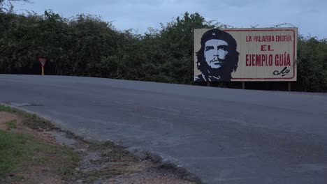 communist propaganda billboards line a road in cuba with classic old car passing