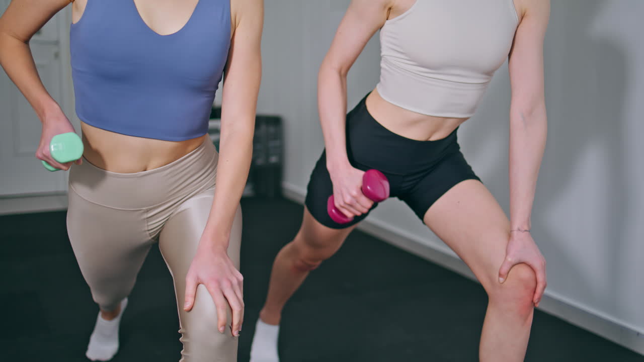 Strong athletes training dumbbells at home studio closeup. Women exercising body
