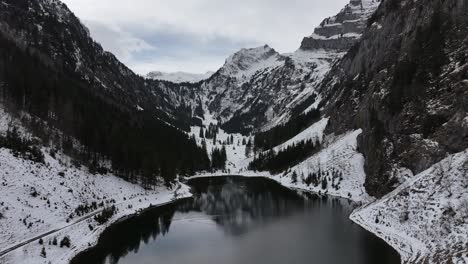 una vista aérea revela la tranquilidad de tahlalpsee en filzbach, glarus nord, suiza, donde los picos de las montañas cubiertas de nieve enmarcan el sereno lago en el valle, con belleza natural y paz.